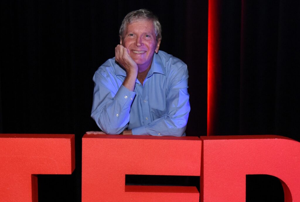 Jim leaning on TEDx logo